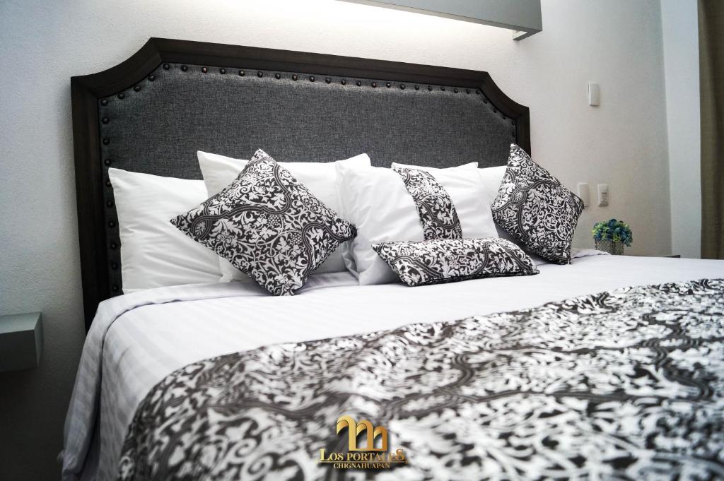 a bed with black and white pillows on it at HOTEL LOS PORTALES CHIGNAHUAPAN in Chignahuapan