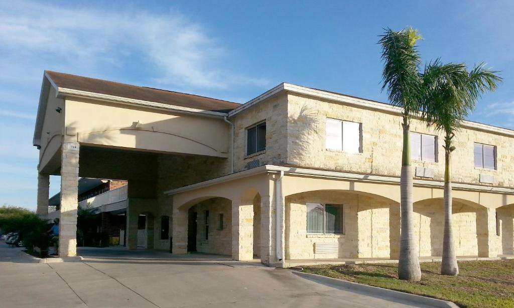 a building with a palm tree in front of it at La Copa Inn Alamo in Alamo