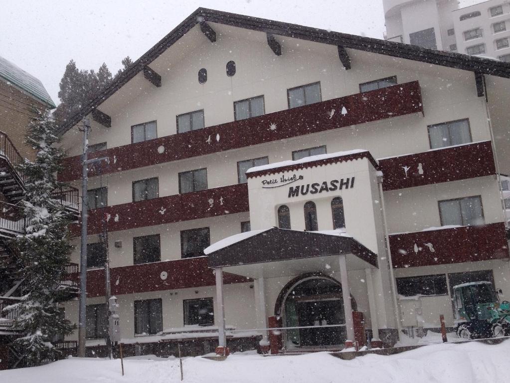 a large building with snow falling in front of it at Naeba Musashi in Yuzawa