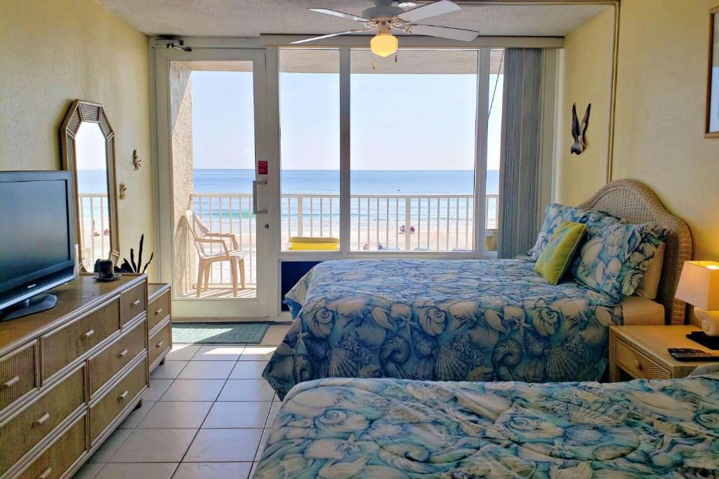 a bedroom with a bed and a television and a balcony at Pirates Cove Condo Unit #227 in Daytona Beach Shores