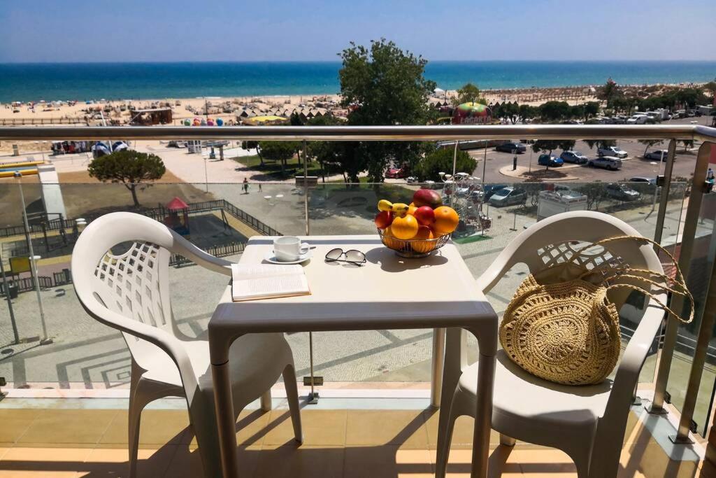 uma mesa e cadeiras numa varanda com vista para a praia em La Francesa Algarve em Monte Gordo