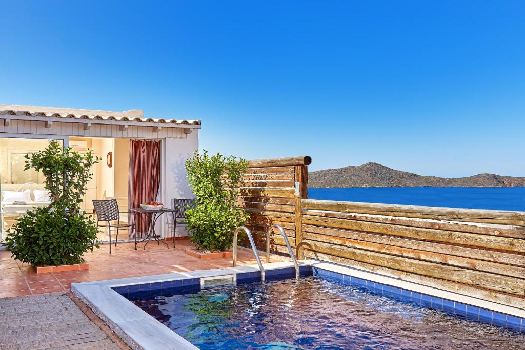 a swimming pool with a wooden fence next to a house at Elounda Eleon Villas in Elounda