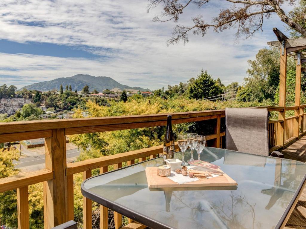 a glass table on a deck with wine glasses at Treetop Hideaway - Taupo Holiday Home in Taupo