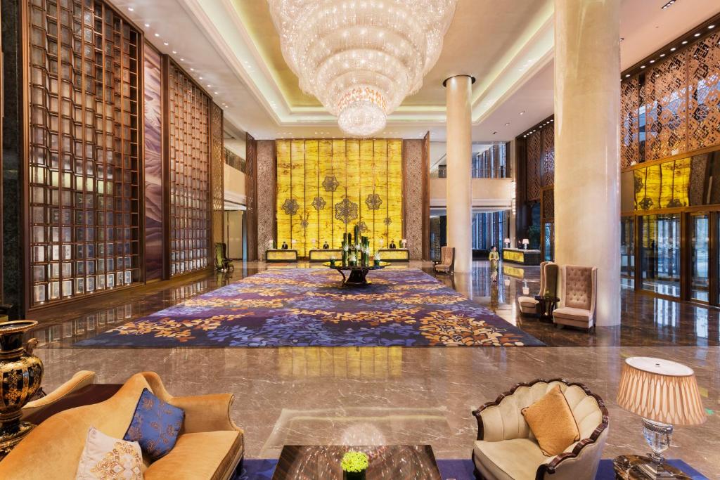 un vestíbulo del hotel con una gran alfombra y una lámpara de araña en Wanda Realm Harbin Hotel en Harbin