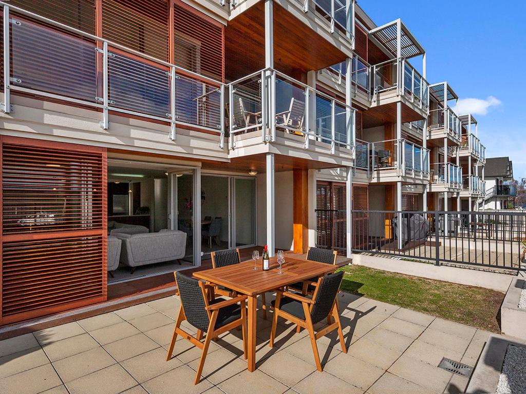 a patio with a wooden table and chairs in front of a building at Roberts Retreat - Taupo Holiday Home in Taupo