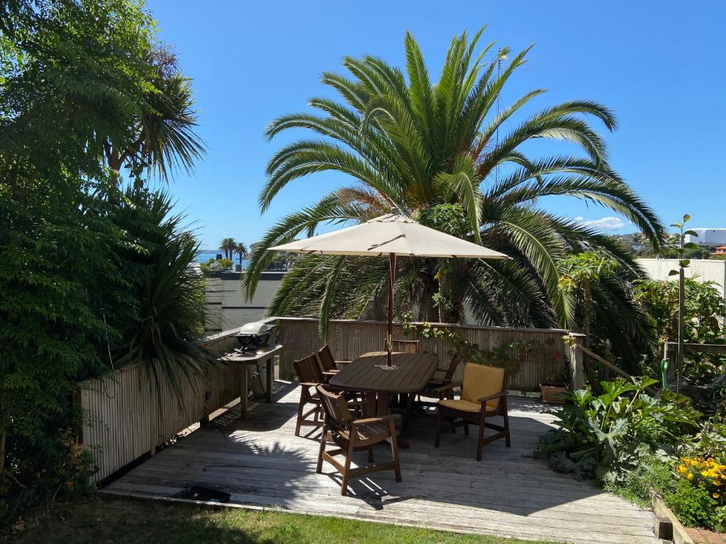 a table and chairs with an umbrella on a patio at Palm Garden Apartment in Auckland