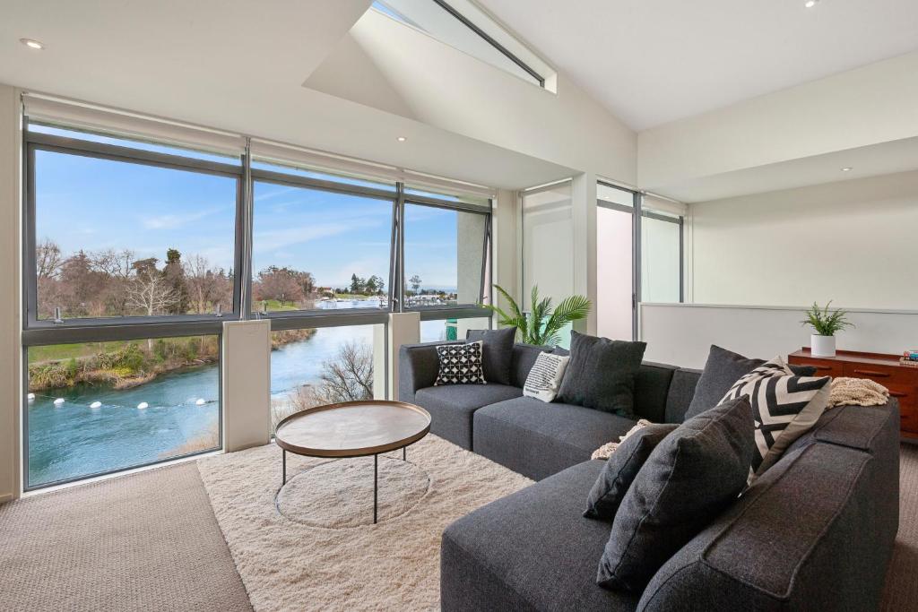 ein Wohnzimmer mit einem Sofa und einem Tisch in der Unterkunft Riverside Villa - Taupo Holiday Home in Taupo