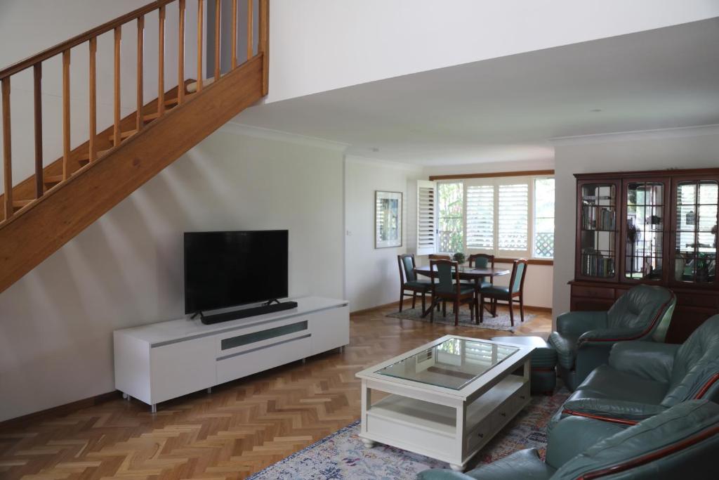 a living room with a couch and a tv at Pacific Palms Thirroul Beach NSW in Thirroul