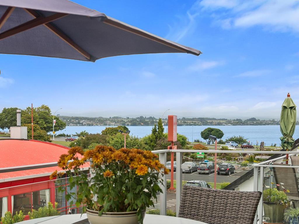 a balcony with flowers and a view of the water at Relax on Roberts - Taupo Holiday Home in Taupo