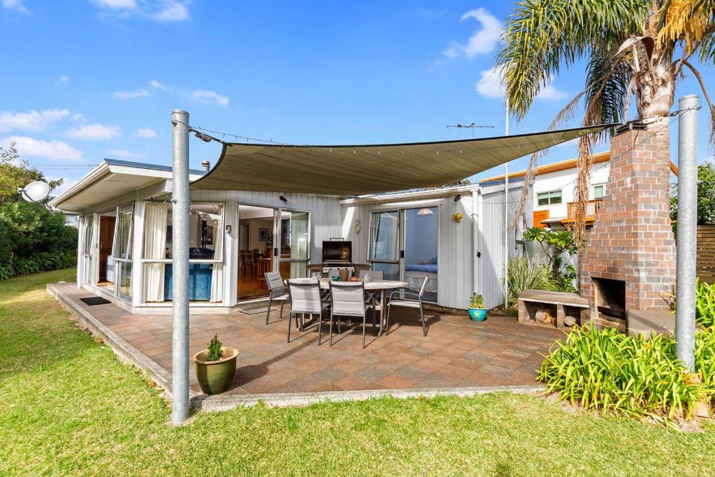 un patio con mesa y sillas bajo un dosel en Matapouri Beach Family Haven - Matapouri Home en Matapouri