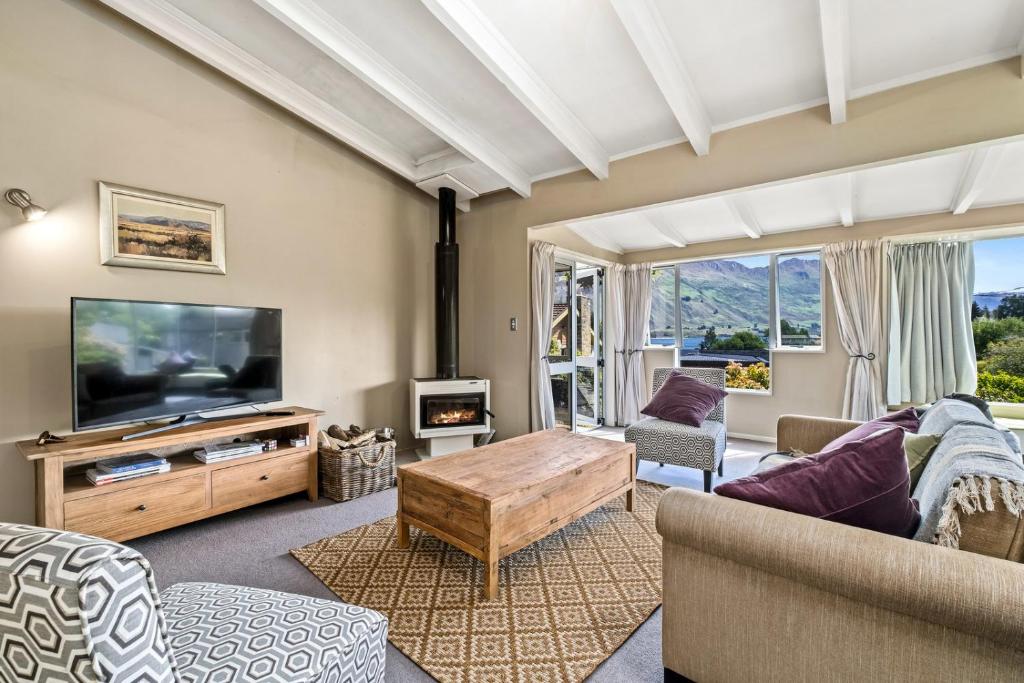 Una sala de estar con un televisor, un sofá y una mesa. en Taha Wai - Wanaka Holiday Home, en Wanaka