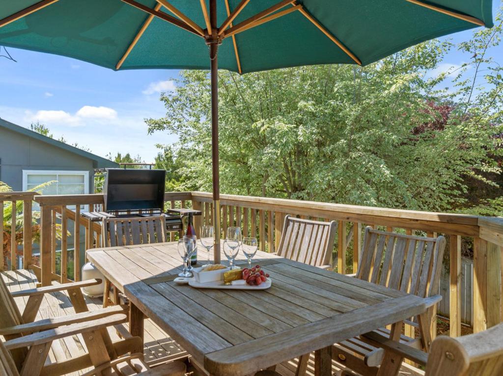 a wooden table with an umbrella on a deck at Family at Wharewaka - Wharewaka Holiday Home in Taupo