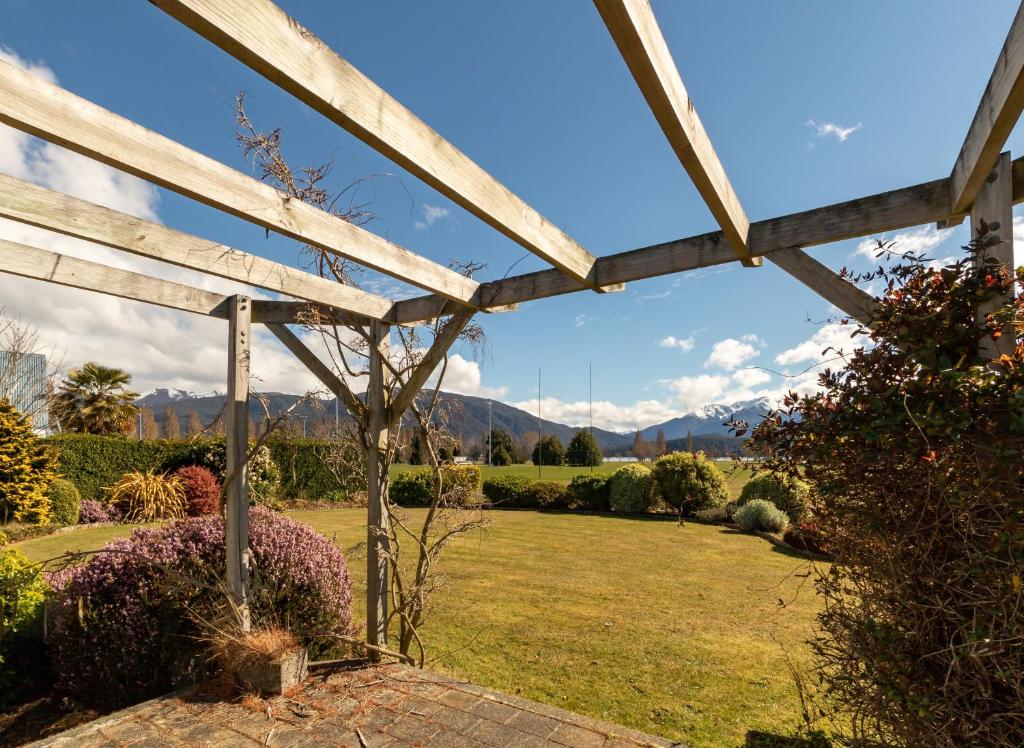 a wooden pergola with a view of a garden at Kepler Retreat - Te Anau Holiday Home in Te Anau
