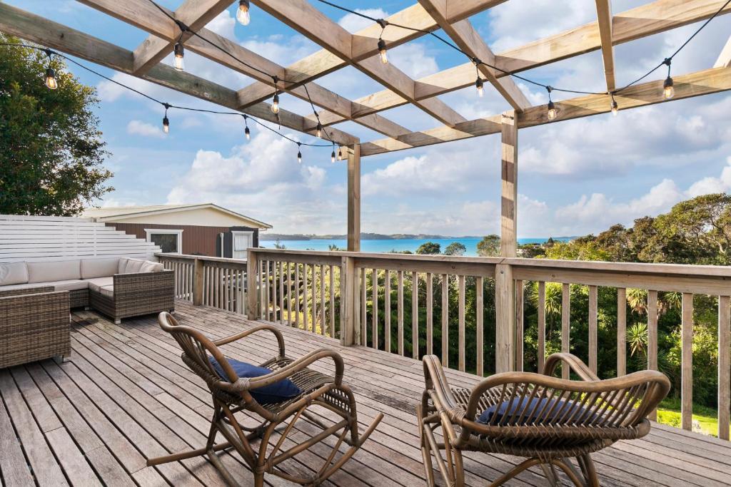 una terraza de madera con 2 sillas y 1 cama en The Cottage - Snells Beach Holiday Home, en Snells Beach