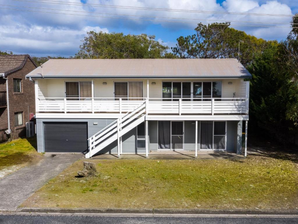 a white house with a porch and a garage at Seaview Getaway in Dunbogan