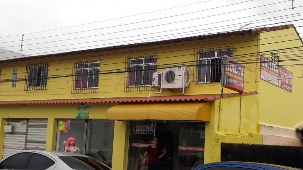 un bâtiment jaune avec un homme debout à l'extérieur dans l'établissement LOFT, à Iguaba Grande