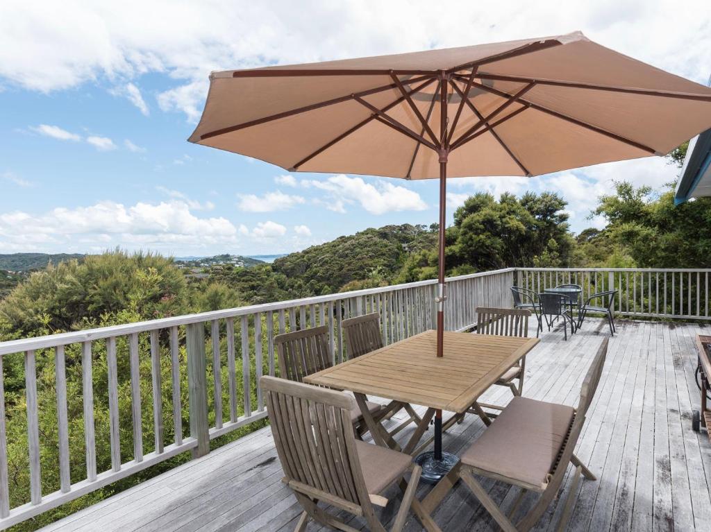 une table en bois avec un parasol sur une terrasse dans l'établissement Skipper's Haven - Opua Holiday Home, à Opua
