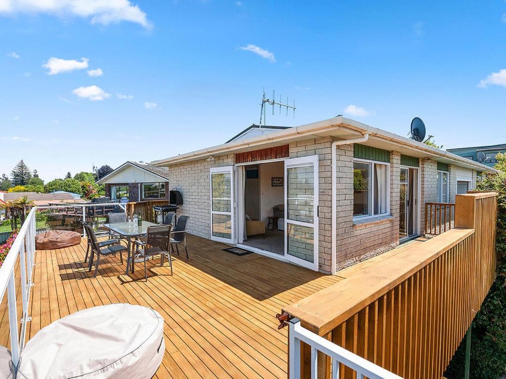 ein Haus mit einer Terrasse mit einem Tisch und Stühlen in der Unterkunft Central Riverside Retreat - Taupo Holiday Home in Taupo