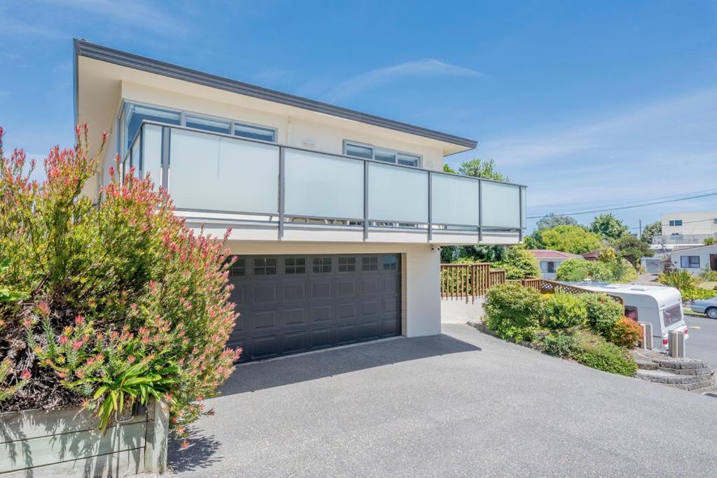 a house with a balcony on top of a garage at Sun on Seaview - Paraparaumu Beach Holiday Home in Paraparaumu Beach