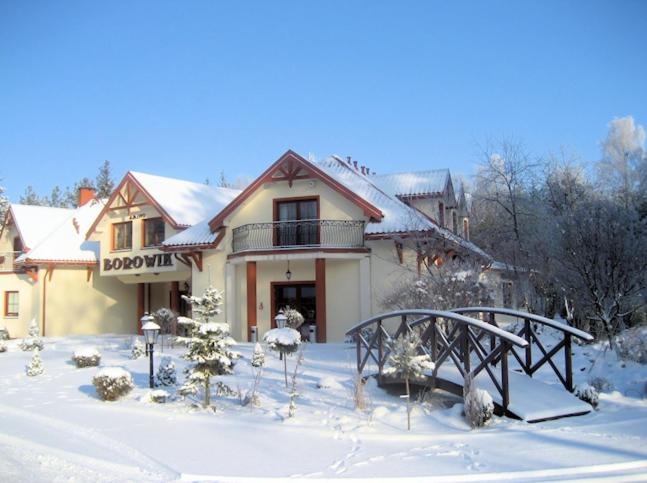 a house in the snow with a bridge in front at Zajazd Borowik in Ostrołęka