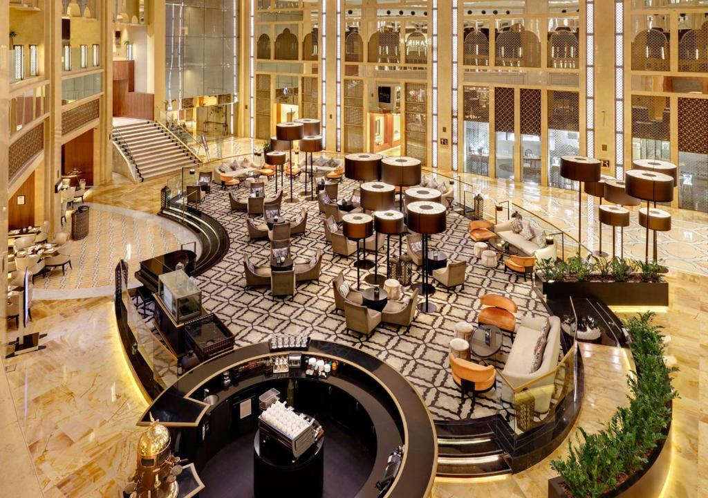 un gran vestíbulo con mesas y sillas en un edificio en The H Dubai en Dubái