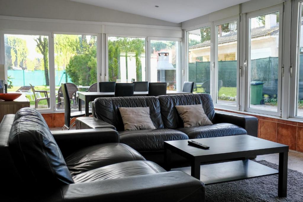 a living room with couches and a table and windows at Chalet Medina del Campo entrepinares in El Campillo