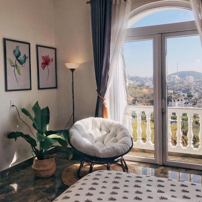a room with a white chair and a large window at Sally Villa Homestay in Da Lat
