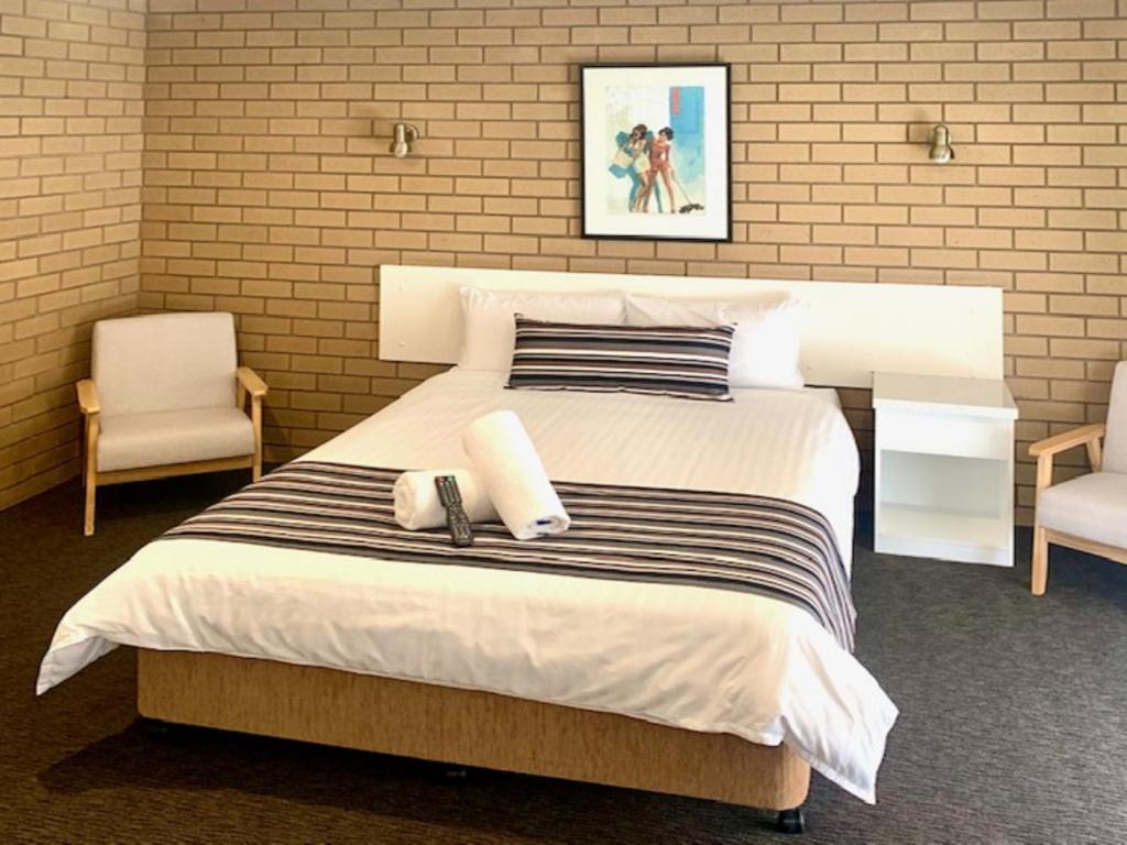 a bedroom with a large white bed and two chairs at Albury City Motel in Albury