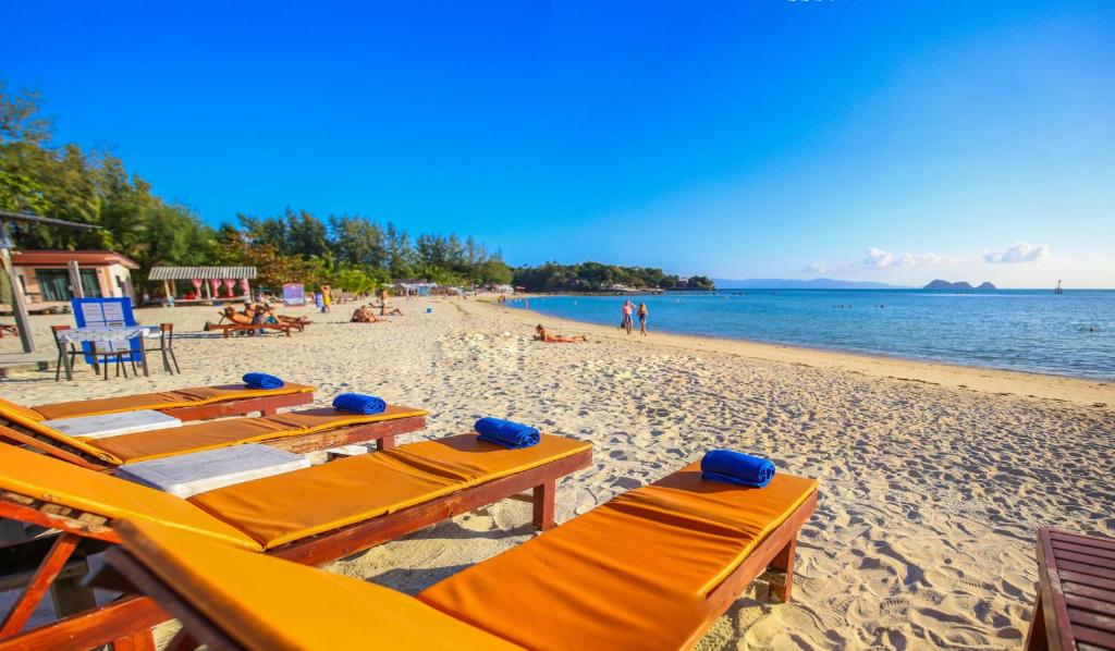 a beach with tables and chairs and the ocean at Laemson Resort in Srithanu