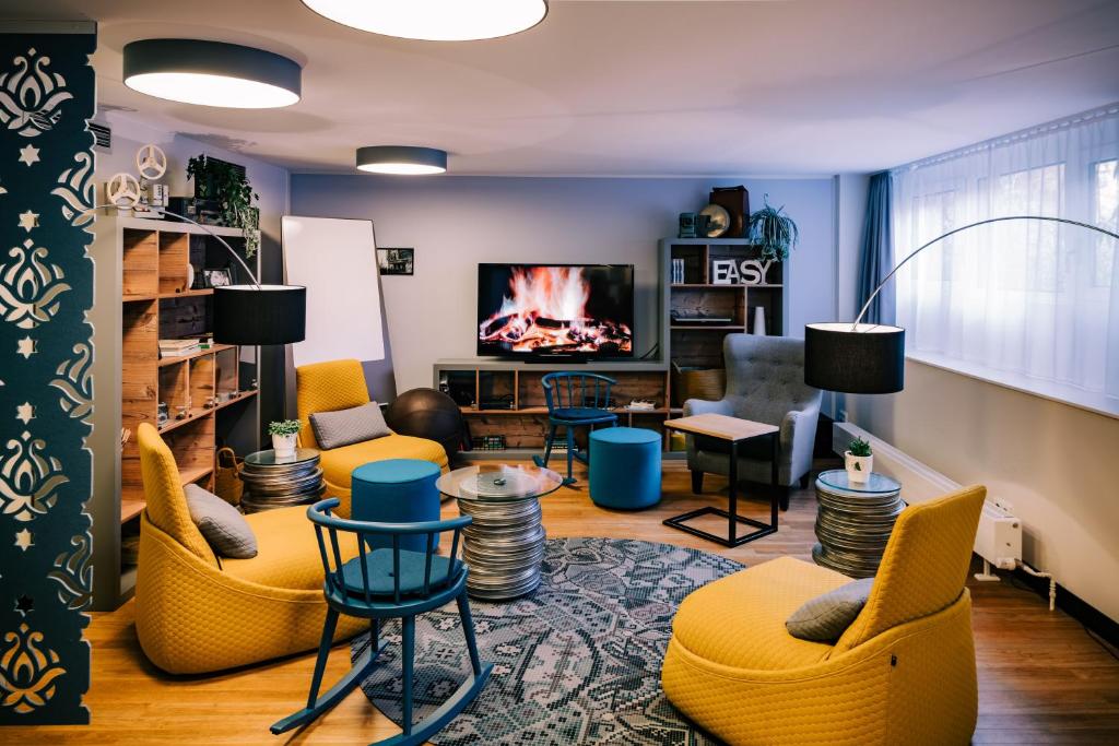 a living room with yellow chairs and a fireplace at Vienna House Easy by Wyndham München in Munich