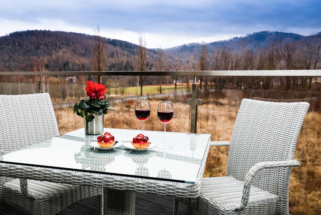 - une table avec deux verres de vin sur le balcon dans l'établissement Apartament Szyndzielnia, à Bielsko-Biała