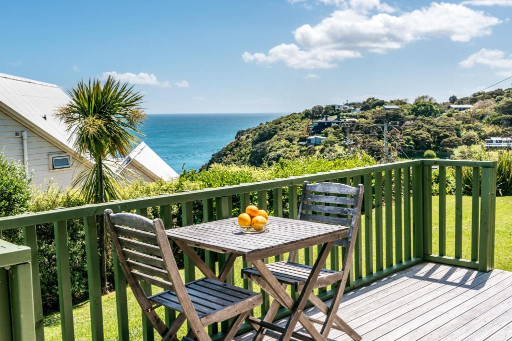 un tavolo e due sedie su una terrazza con vista sull'oceano di The Island Gem - Oneroa Holiday Home a Oneroa