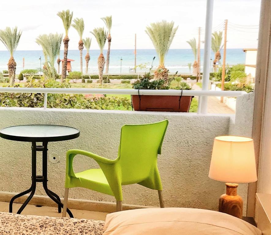 a room with a green chair and a table and the beach at Iason Seaview home in Latchi in Polis Chrysochous