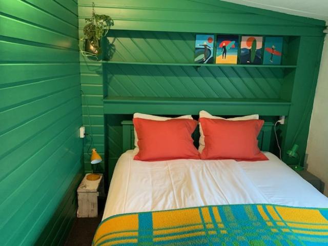 Bett mit roten Kissen in einem grünen Zimmer in der Unterkunft Hotel B&B Altijd Wad in West-Terschelling