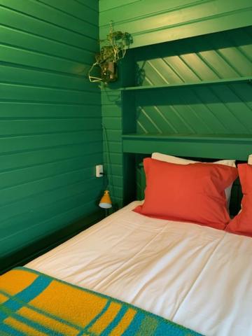 a bedroom with green walls and a bed with red pillows at Hotel B&B Altijd Wad in West-Terschelling