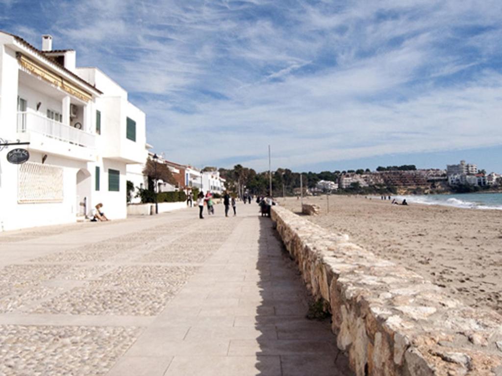 a beach with a building and people walking on it at AT303 Botigues de Mar in Altafulla