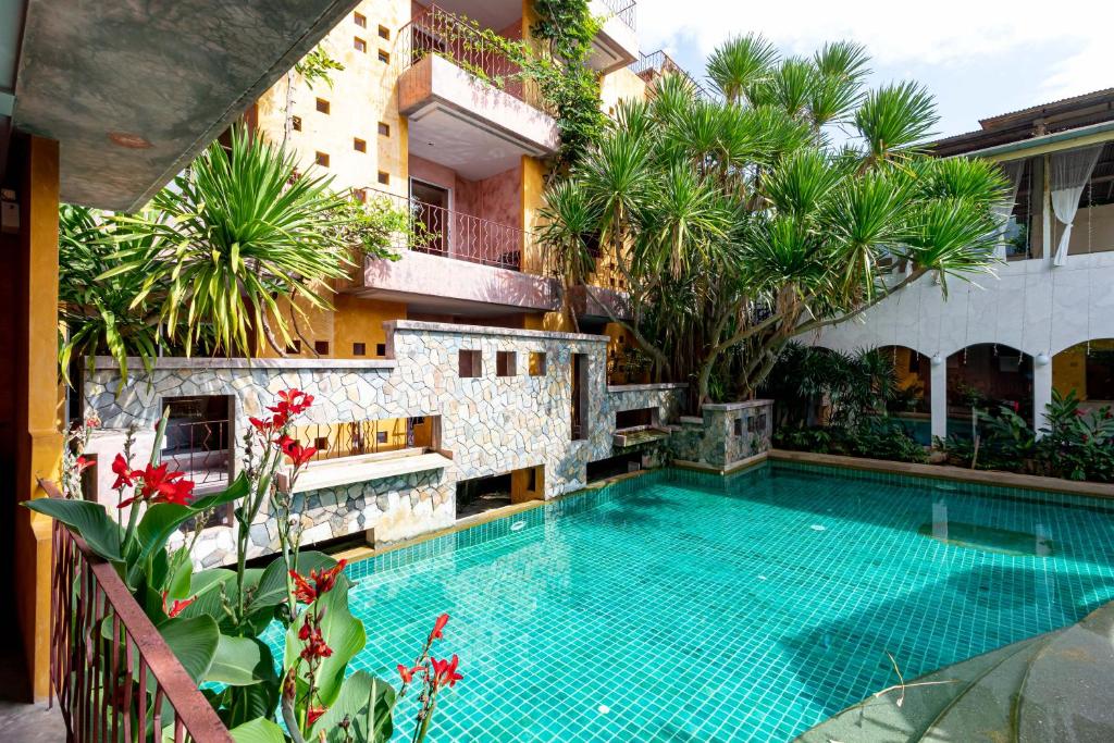 a swimming pool in front of a building with palm trees at The Weenee Boutique in Hat Yai