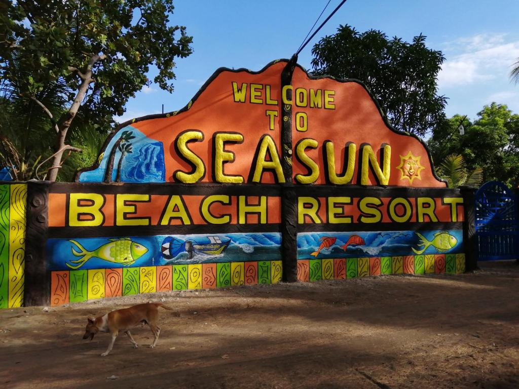 un perro de pie frente a un cartel de bienvenida al complejo Seascum Beach en Seasun Beach Resort & Hotel, en Santa Cruz
