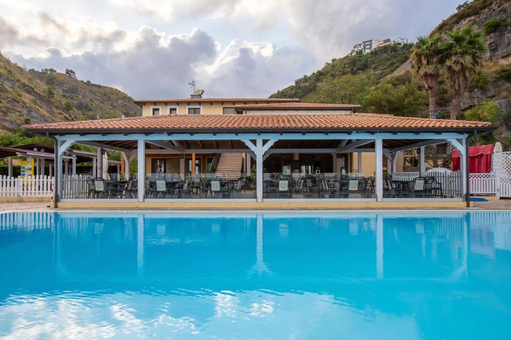ein Resort mit einem blauen Pool vor einem Gebäude in der Unterkunft Arcomagno Beach Resort in San Nicola Arcella