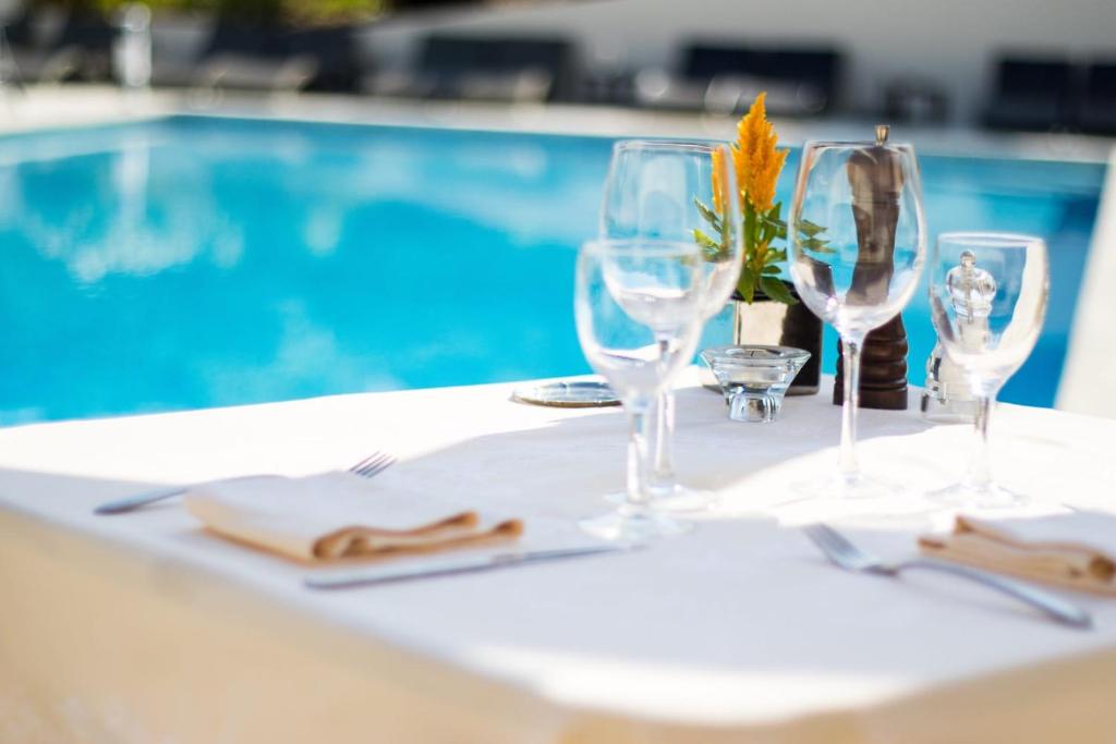 - une table avec des verres à vin sur une table en face d'une piscine dans l'établissement Le Mas Bellevue, à Saint-Tropez