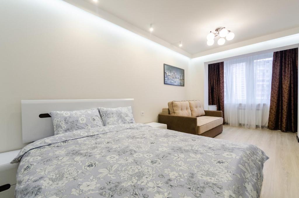 a white bedroom with a bed and a chair at ARTAL Apartment on Obolonsky avenue 31 in Kyiv