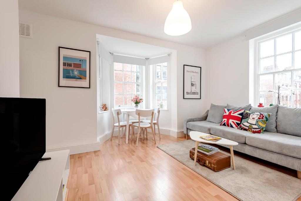 a living room with a couch and a table at Modern One Bedroom Victoria Apartment in London