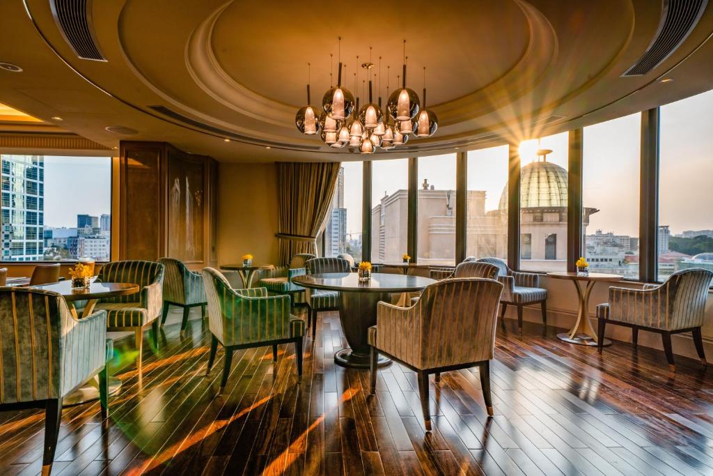 a restaurant with a chandelier and tables and chairs at Caravelle Saigon in Ho Chi Minh City