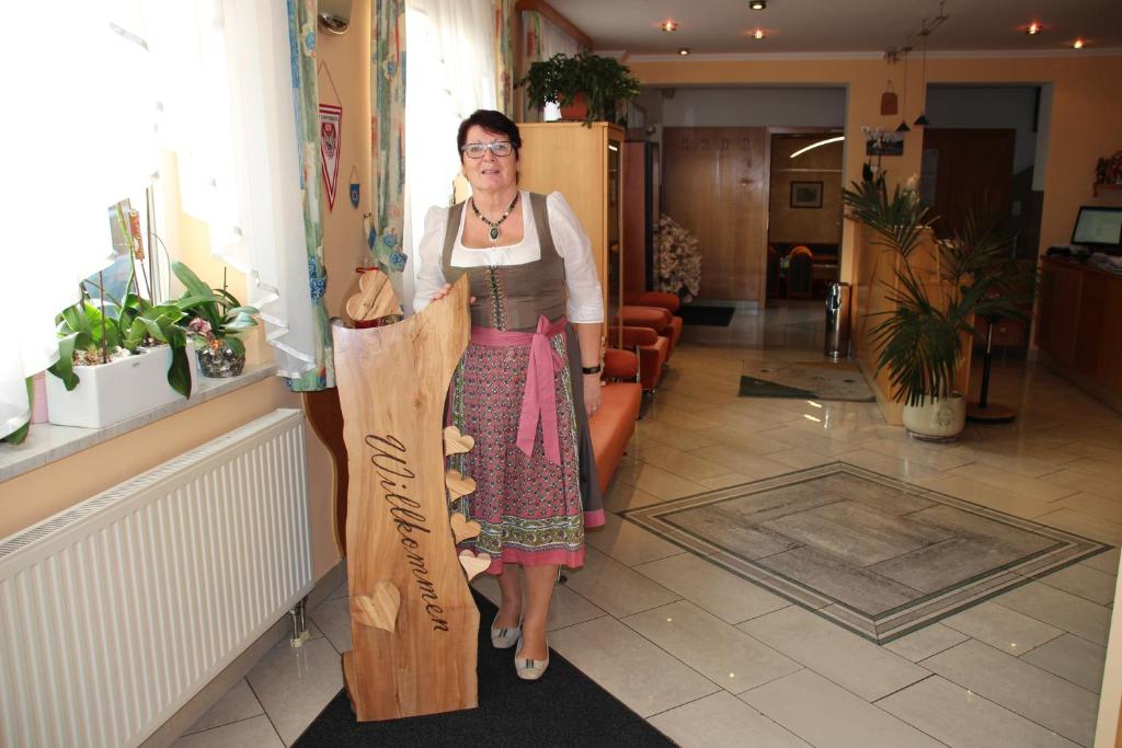 una mujer está de pie junto a un cartel de madera en Hotel Lang, en Leibnitz