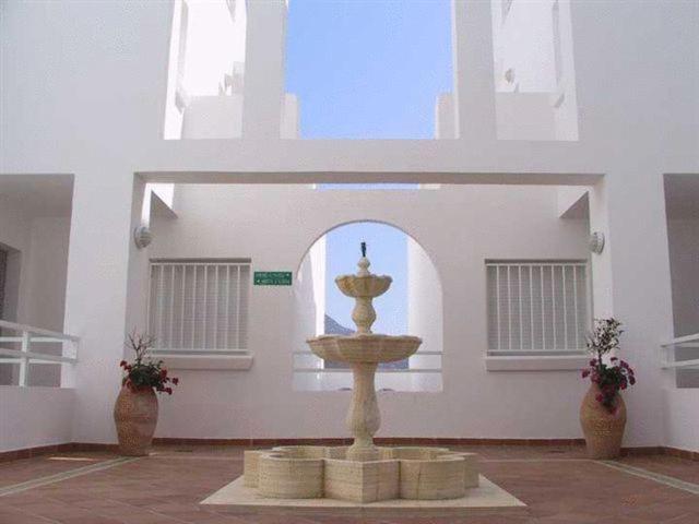 a fountain in the middle of a room with two vases at Apartahotel Vistamar San José in San José