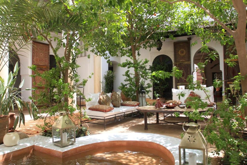 un patio con tavolo, sedie e alberi di Riad Karmela a Marrakech