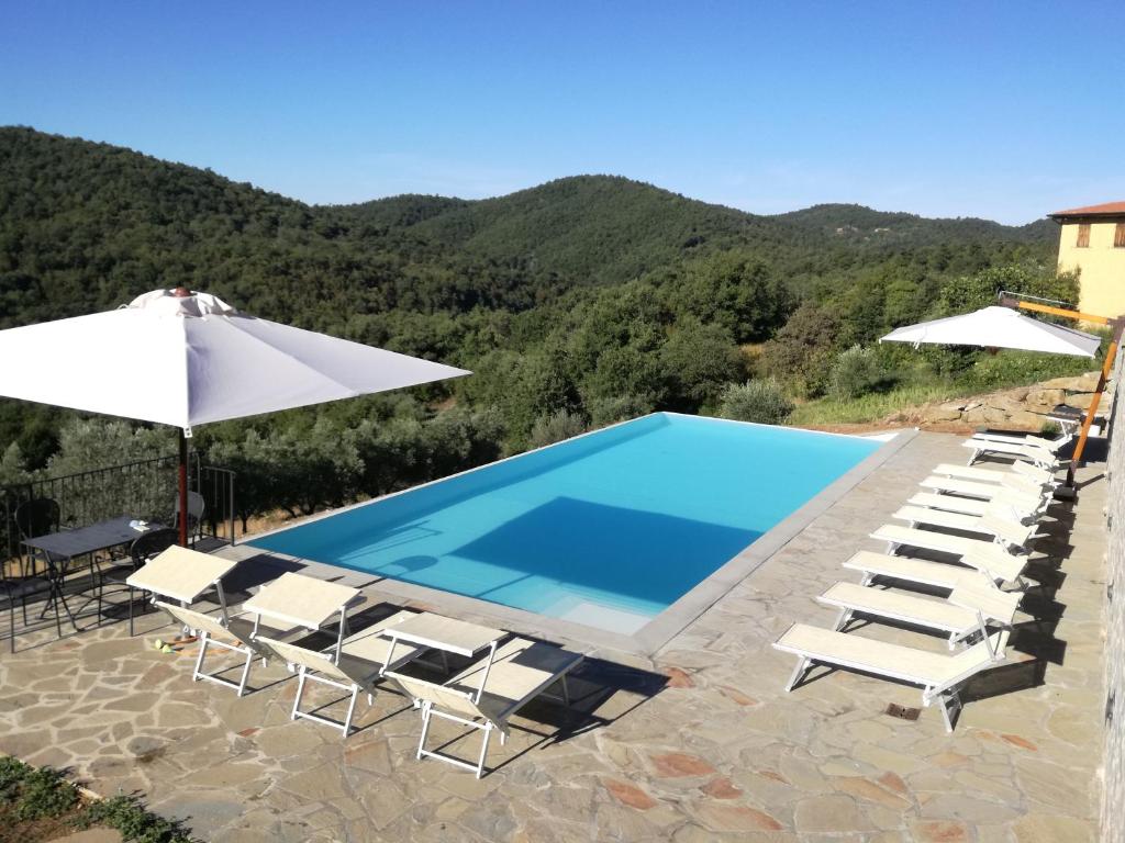 a villa with a swimming pool and chairs and an umbrella at Locanda del Viandante - Valle Apartments & Pool in Anghiari