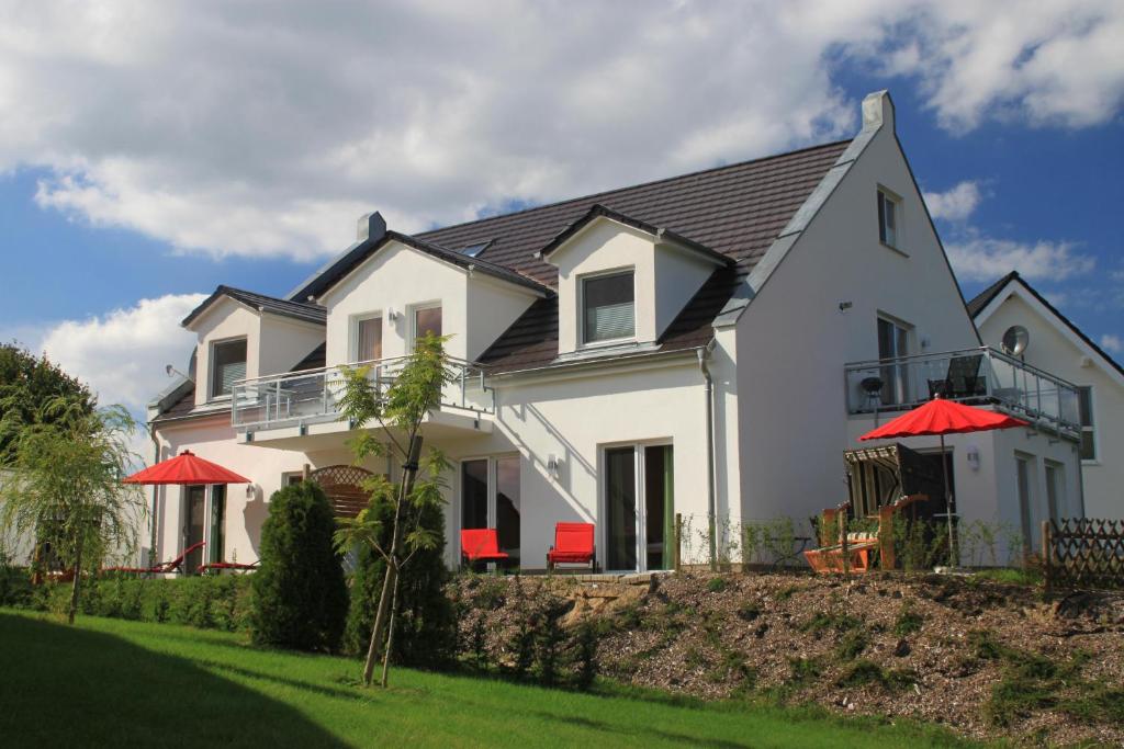 ein weißes Haus mit roten Sonnenschirmen im Hof in der Unterkunft Villa Harmonie W1 in Göhren-Lebbin
