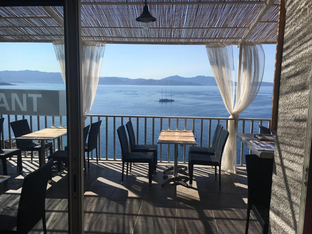 Un balcón con mesas y sillas y vistas al océano. en Bel Mare en Cargèse