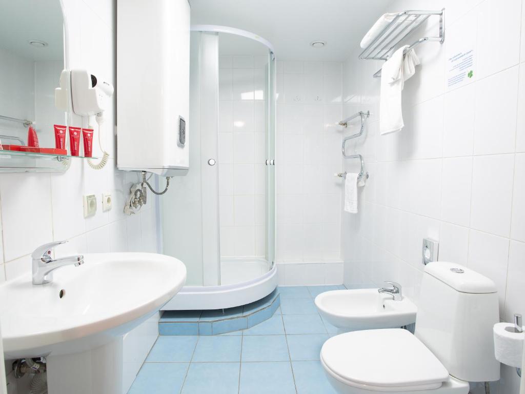 a bathroom with a sink and a toilet and a shower at AZIMUT Hotel Kemerovo in Kemerovo